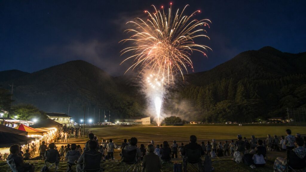 東吾妻町スポーツ広場の芝生と山あいに上がる花火を表現した編集用画像