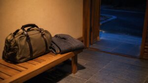 夜の外出から宿へ戻る場面を表す旅行かばんの生成イメージ。実在する宿の写真ではありません。