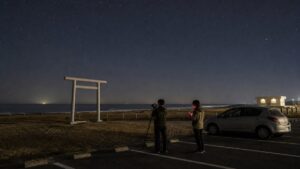 釣ヶ崎海岸を想起させる鳥居と太平洋を駐車場から安全に撮影する旅行者のAI生成イメージ